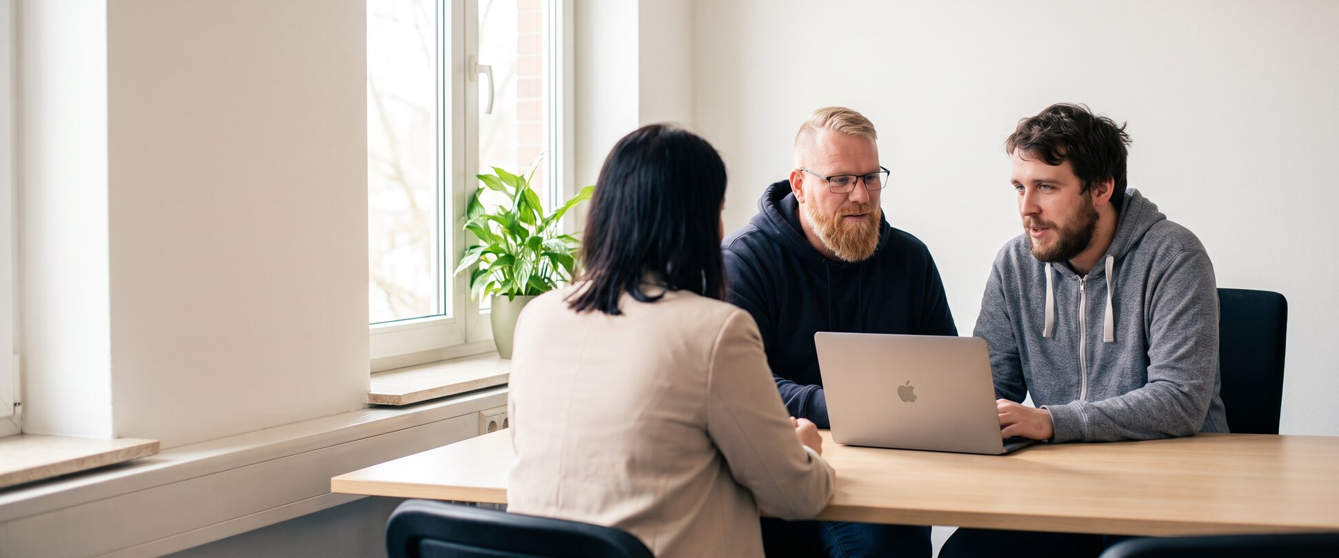 KI-generierte Szene: Florian und Philipp Hesse im hellen Büro bei einer Besprechung mit einer Kundin